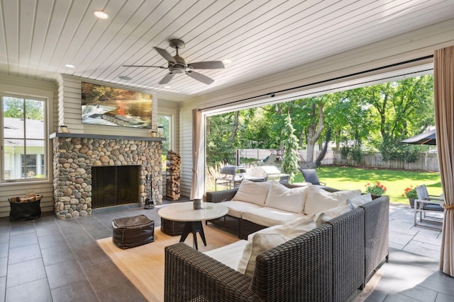 view of patio / terrace with a fenced backyard, a ceiling fan, and an outdoor living space with a fireplace