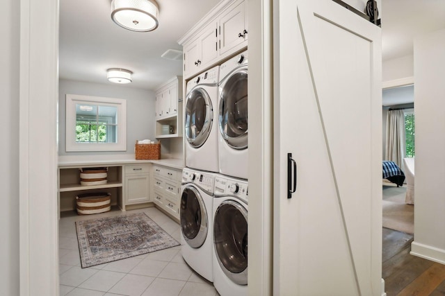 washroom featuring washing machine and dryer, light tile patterned floors, and cabinet space