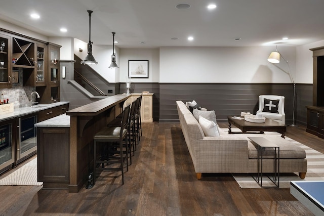 bar featuring a sink, a wainscoted wall, wet bar, wine cooler, and dark wood-type flooring