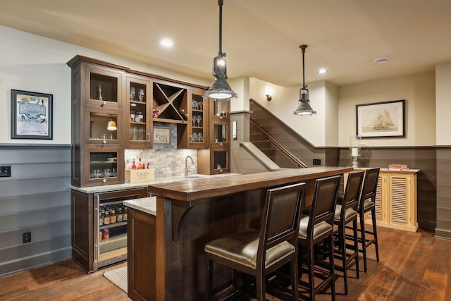 bar featuring indoor wet bar, beverage cooler, tasteful backsplash, dark wood finished floors, and decorative light fixtures