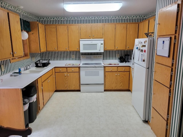 kitchen with white appliances, light floors, a sink, light countertops, and brown cabinets