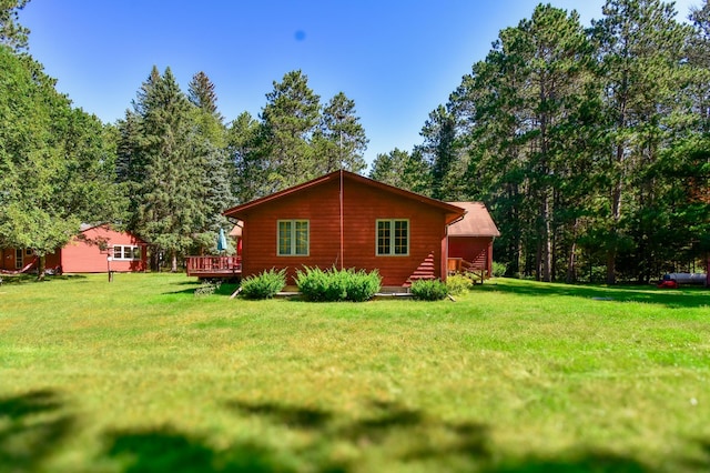 rear view of property featuring a wooden deck and a lawn