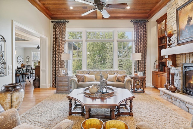 living room with plenty of natural light, a stone fireplace, and wood ceiling