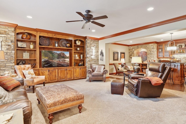 carpeted living room featuring built in shelves, ceiling fan, and ornamental molding