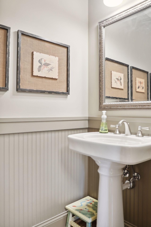 bathroom featuring sink and wooden walls