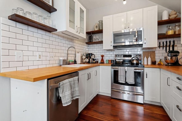 kitchen with appliances with stainless steel finishes, white cabinetry, butcher block counters, sink, and tasteful backsplash