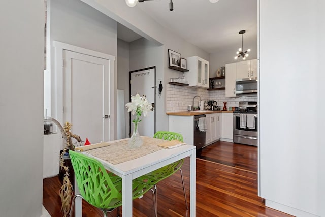 kitchen with white cabinetry, tasteful backsplash, decorative light fixtures, stainless steel appliances, and dark hardwood / wood-style flooring