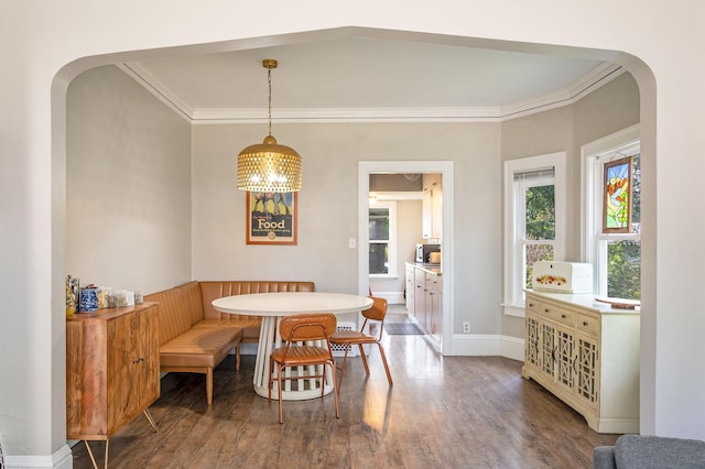 dining room featuring breakfast area, wood-type flooring, ornamental molding, and a chandelier