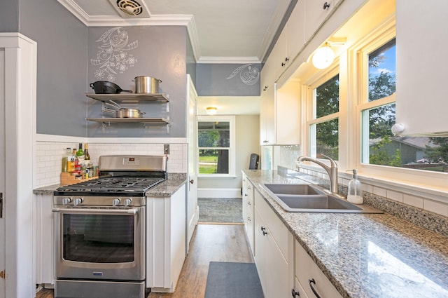 kitchen featuring gas stove, white cabinetry, sink, and a wealth of natural light