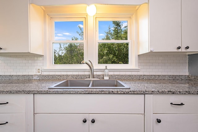 kitchen featuring white cabinets, light stone countertops, sink, and tasteful backsplash