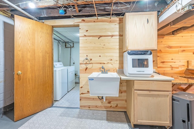 clothes washing area with wooden walls, sink, and washer and dryer