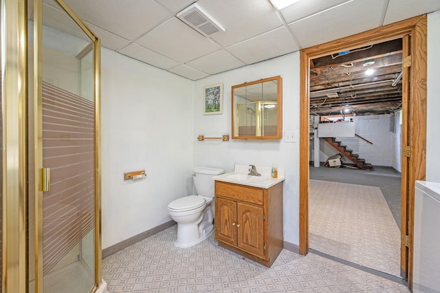 bathroom with a drop ceiling, toilet, an enclosed shower, and vanity