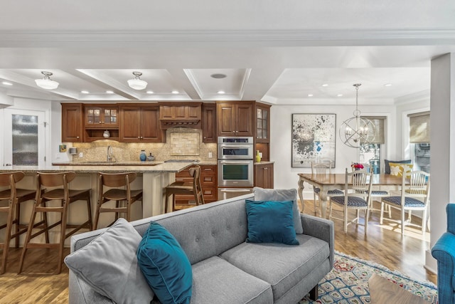 living room with light wood-type flooring, crown molding, and a chandelier