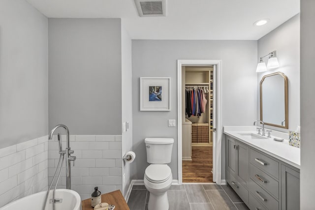 bathroom with vanity, a bathtub, toilet, tile walls, and hardwood / wood-style floors