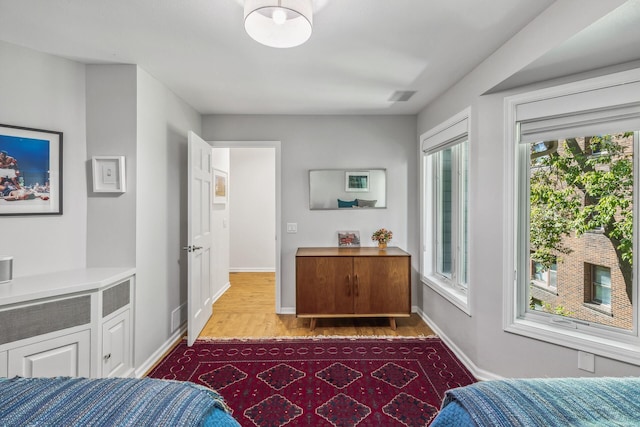 bedroom with multiple windows and light wood-type flooring