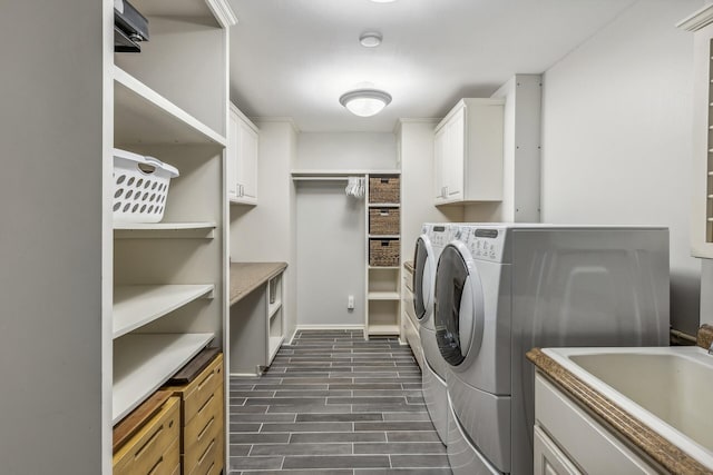 laundry area with dark wood-type flooring, washer and dryer, sink, and cabinets