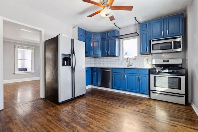 kitchen with blue cabinets, appliances with stainless steel finishes, dark hardwood / wood-style floors, and backsplash