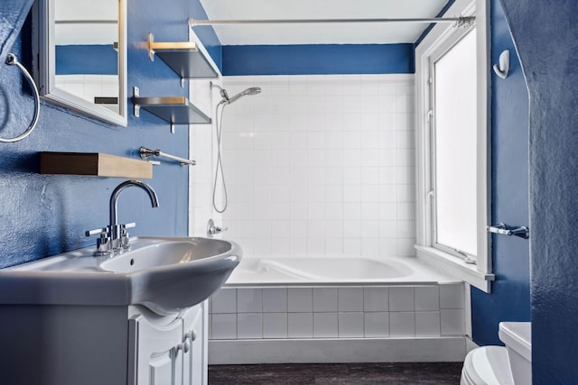 full bathroom with vanity, toilet, tiled shower / bath combo, and wood-type flooring