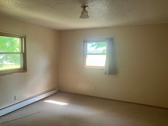 unfurnished room featuring a textured ceiling, a baseboard heating unit, and plenty of natural light