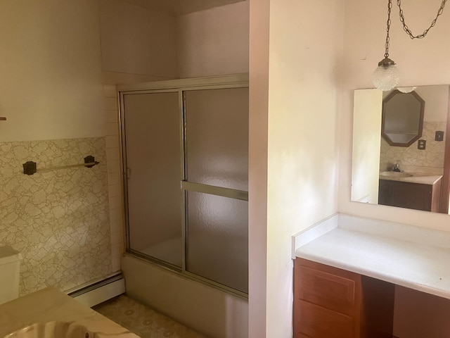 bathroom with vanity, baseboard heating, and bath / shower combo with glass door