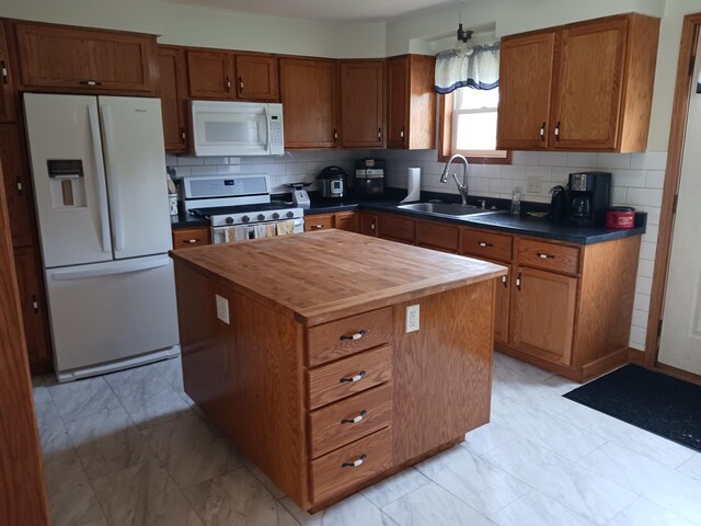 kitchen featuring white appliances, butcher block countertops, decorative backsplash, a sink, and brown cabinets