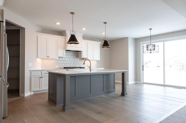 kitchen with an island with sink and white cabinets