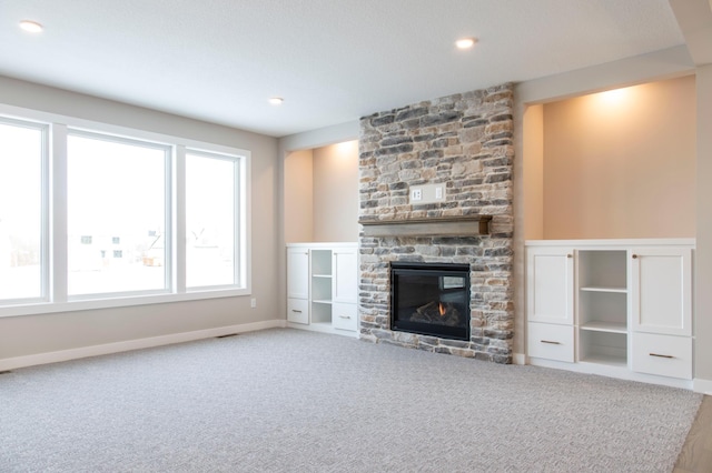 unfurnished living room with a stone fireplace and carpet