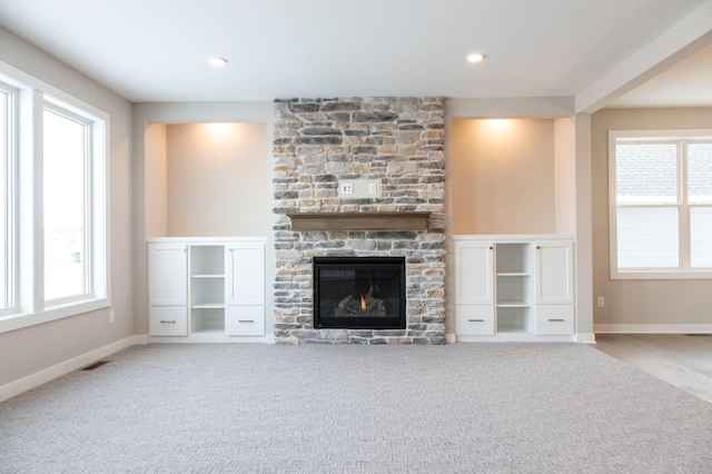 unfurnished living room with light carpet and a stone fireplace