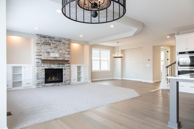 unfurnished living room featuring an inviting chandelier, hardwood / wood-style flooring, and a fireplace