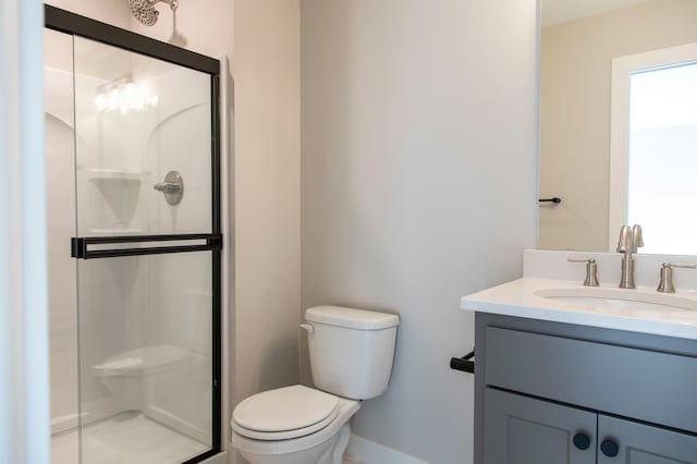 bathroom with a shower with door, vanity, and toilet