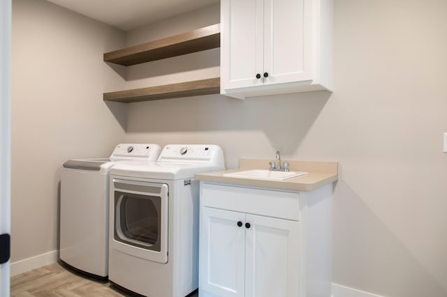 clothes washing area with cabinets, sink, and independent washer and dryer