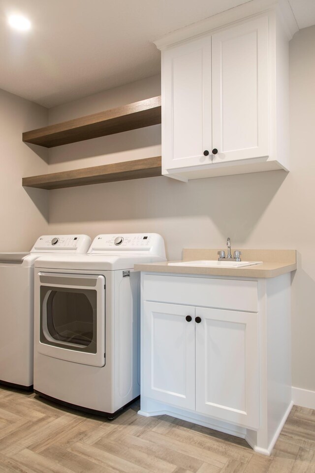 laundry room with sink, cabinets, washer and dryer, and light parquet floors