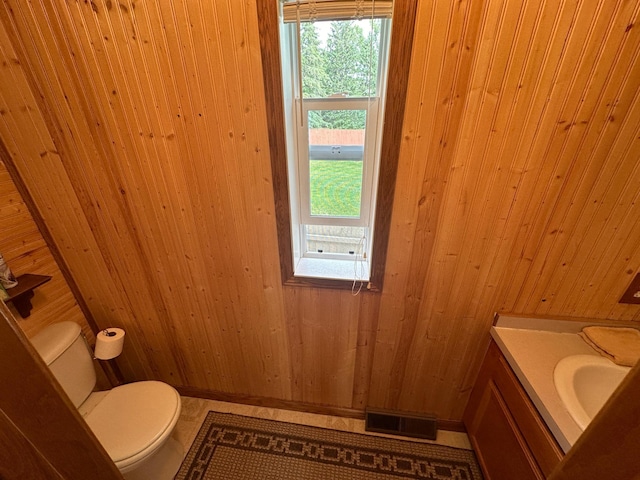 bathroom with toilet, wooden walls, tile patterned floors, vanity, and wooden ceiling