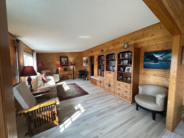 living room featuring a textured ceiling, vaulted ceiling, wood walls, and light wood-type flooring