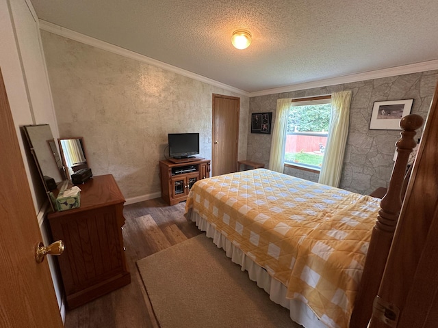 bedroom with baseboards, ornamental molding, a textured ceiling, and wood finished floors