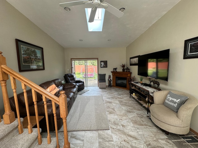 living room featuring stairway, marble finish floor, a ceiling fan, and vaulted ceiling with skylight