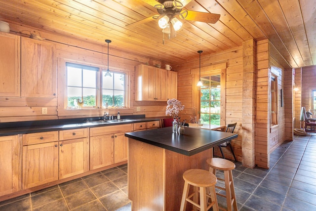 kitchen with wood walls, hanging light fixtures, a center island, and ceiling fan