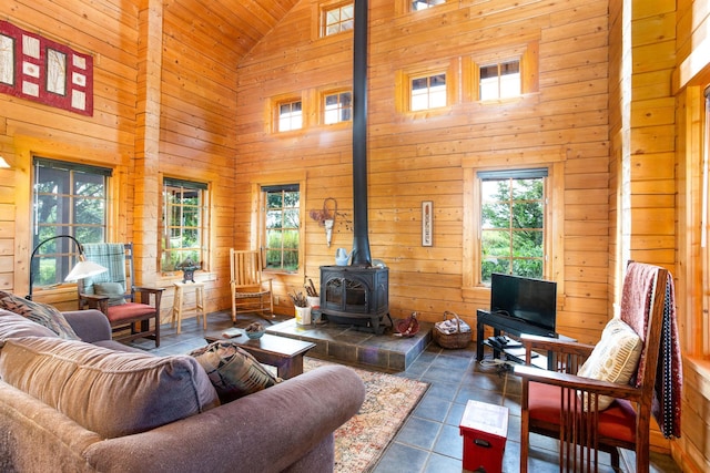 tiled living room featuring high vaulted ceiling, wood walls, and a wood stove