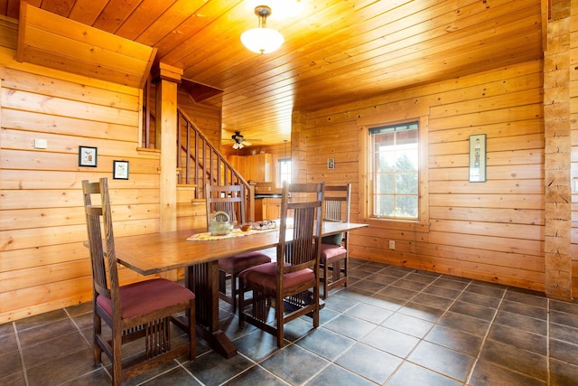 dining area featuring stairway, wood walls, wood ceiling, and dark tile patterned floors