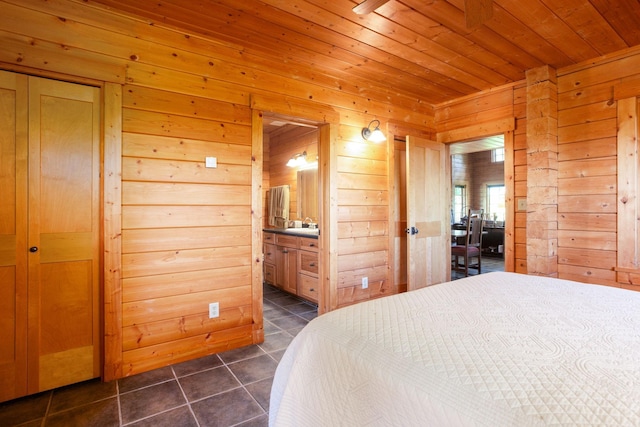 bedroom with wooden ceiling, wooden walls, ensuite bathroom, and dark tile patterned flooring