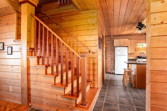 staircase featuring tile patterned floors, wooden walls, and wooden ceiling