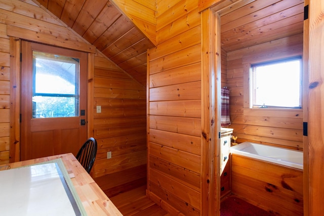 interior space with a bath, wood walls, wood ceiling, and a healthy amount of sunlight