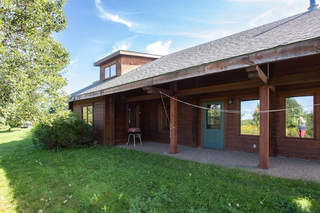 back of property with a yard, a patio, and roof with shingles