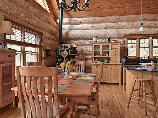 dining room with a healthy amount of sunlight, light wood-type flooring, and rustic walls