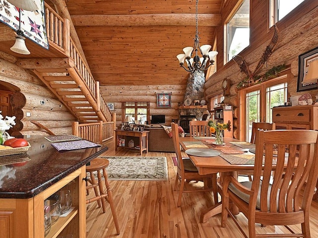 dining room with rustic walls, high vaulted ceiling, a fireplace, and light wood-type flooring