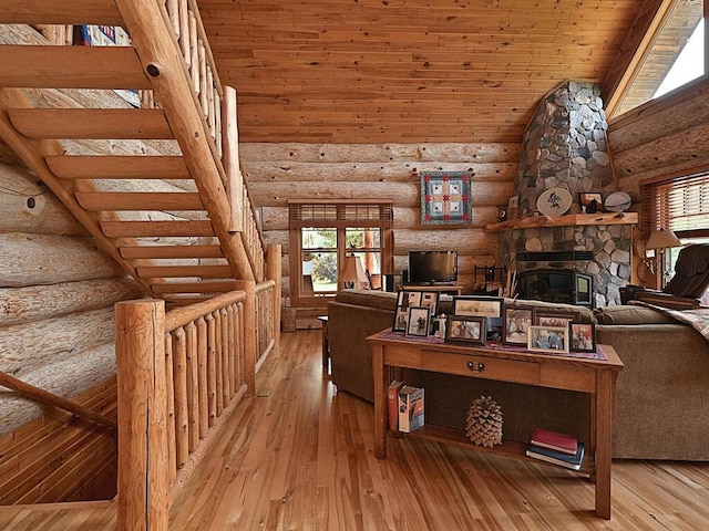 unfurnished living room with rustic walls, wood ceiling, hardwood / wood-style flooring, and a stone fireplace