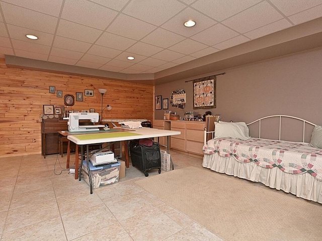 bedroom with a paneled ceiling, wood walls, and light tile patterned flooring