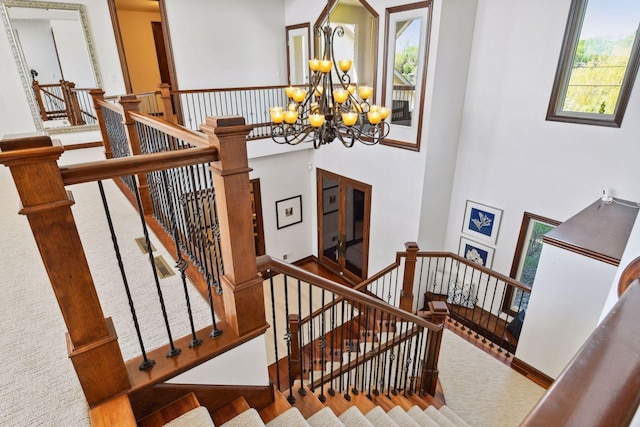 stairs featuring plenty of natural light, a chandelier, a high ceiling, and baseboards
