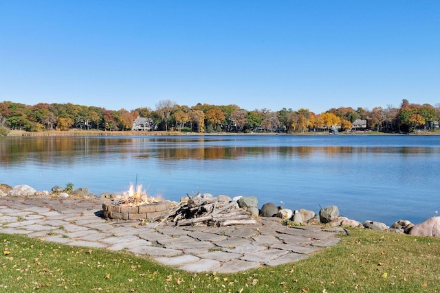 water view with an outdoor fire pit and a forest