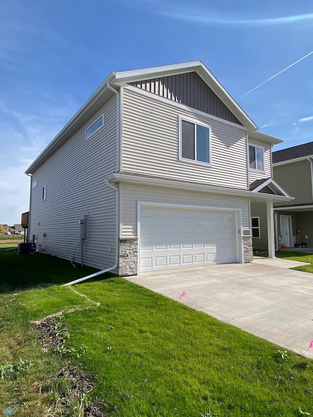 view of home's exterior with central AC unit, driveway, stone siding, an attached garage, and a lawn